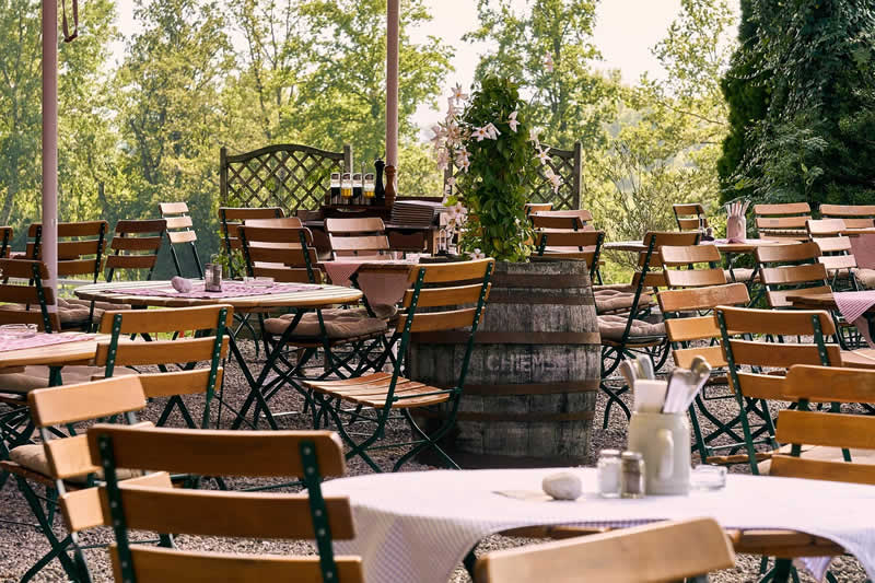 Leerer Gastgarten mit angrenzenden B&auml;umen